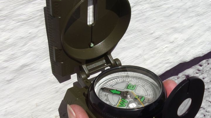 Eine Hand h&auml;lt einen Kompass, der ge&ouml;ffnet ist, w&auml;hrend er auf eine Wand zeigt, m&ouml;glicherweise um Stahltr&auml;ger zu finden.