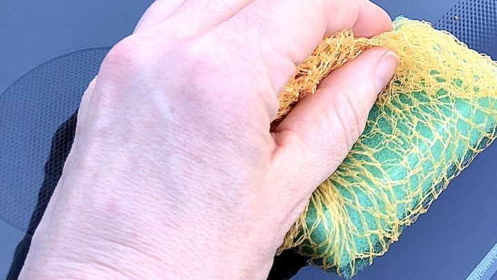 Eine Hand reinigt die Autoscheibe mit einem speziellen Schwamm, um Insektenschmutz zu entfernen.