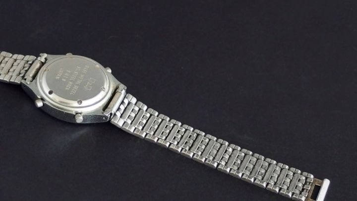 Eine silberne Uhr liegt auf einem schwarzen Untergrund und wartet darauf, gereinigt zu werden, um wieder gut auszusehen.