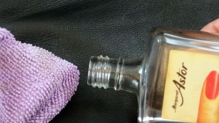 Eine Leder-Aktentasche wird mit einem Reinigungstuch und einer Flasche zum Entfernen von Kratzern behandelt.