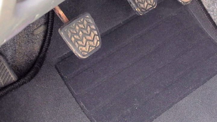 Eine Fu&szlig;matte liegt vor einem Fahrpedal im Auto, wobei sie stabilisiert werden sollte, um Rutschen zu verhindern.