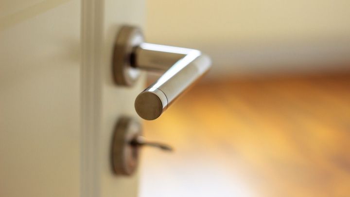 Eine moderne T&uuml;r mit einem Edelstahl-T&uuml;rgriff &ouml;ffnet sich sanft in einen hellen Raum mit Holzboden.