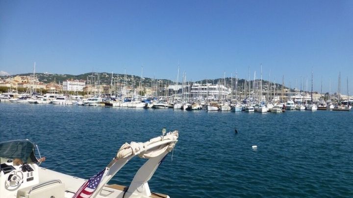 Ein Boot liegt am Hafen mit vielen Yachten im Hintergrund. Der Himmel ist klar, das Wasser ruhig, ideal zum Angeln.