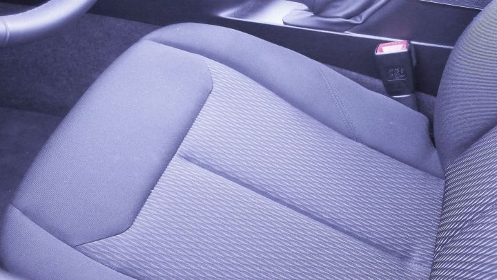 Ein graues Sitzpolster im Auto zeigt eine beigelegte Ecke, wobei die Textur deutlich erkennbar ist.