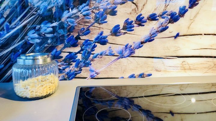 Eine K&uuml;chenr&uuml;ckwand aus Lavendelmotiv dekoriert einen modernen Kochbereich, w&auml;hrend ein Glasbeh&auml;lter mit Nudeln daneben steht.
