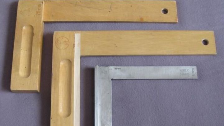 Zwei Schlosserwinkel liegen auf grauem Stoff. Der gr&ouml;&szlig;ere ist aus Holz, der kleinere aus Metall mit Gravur "RIEFLY DIN 875/0".