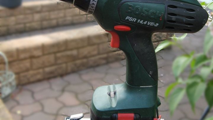 Ein Akkuschrauber steht auf einem Gel-Akku und sieht bereit aus, um in einem Gartenbereich verwendet zu werden.