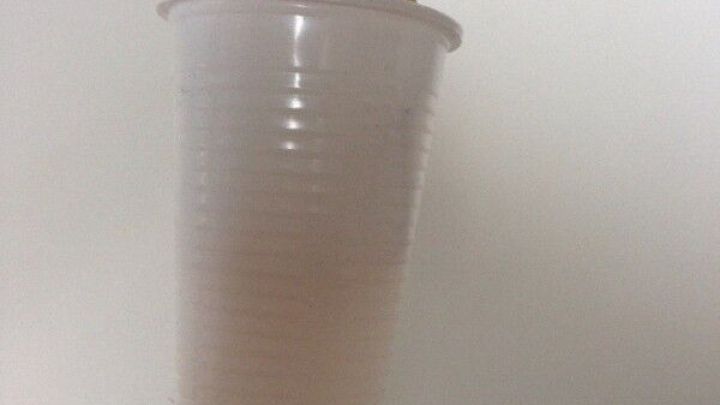 Ein Pinsel mit einem Plastikbecher an der Spitze steht, um beim Streichen das Kleckern zu verhindern.