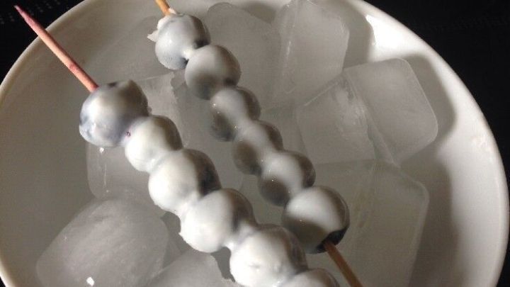 Heidelbeer-Joghurt-Eisspie&szlig;e liegen auf Eisw&uuml;rfeln in einer Sch&uuml;ssel, k&uuml;hl und ansprechend f&uuml;r den Sommer.