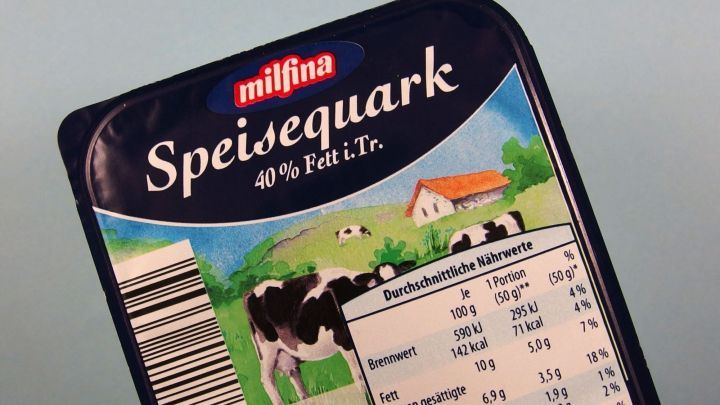 Eine Verpackung von Speisequark zeigt eine Kuh und eine l&auml;ndliche Szene, die Frischhaltung an einem hellen Hintergrund.