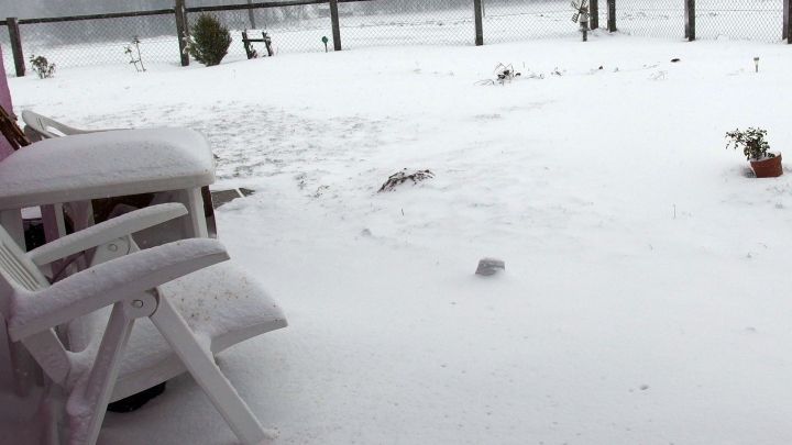 Ein Stuhl liegt im Schnee, w&auml;hrend weitere Schneemassen den Garten bedecken und Landschaft verdecken.