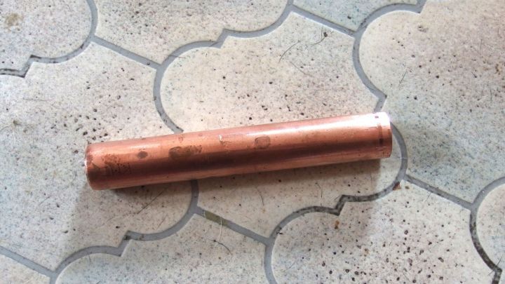 Ein Kupferrohr liegt auf einem gefliesten Boden, das zur Verhinderung von M&uuml;ckenzucht im Wasserfass verwendet wird.