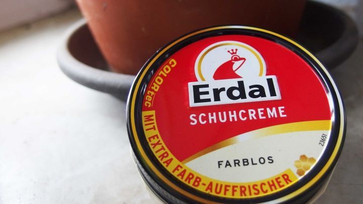 Ein runder Beh&auml;lter mit Schuhcreme steht neben einem Terrakottatopf und zeigt den Einsatz von Schuhcreme zur Wetterfestigkeit.