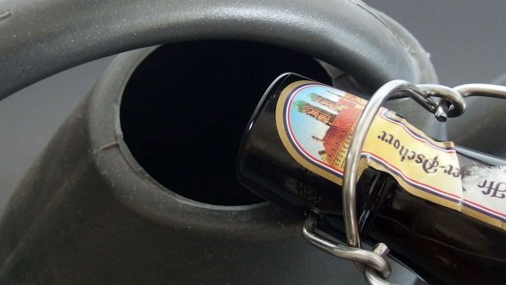 Ein Bierflasche wird in eine Gie&szlig;kanne eingef&uuml;llt, um als Blumend&uuml;nger im Garten verwendet zu werden.