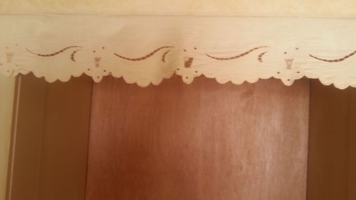 Eine dekorative Vorhangschiene verdeckt niedrige T&uuml;rst&ouml;cke in einem Raum mit warmen Farben und einem Holzt&uuml;rblatt.