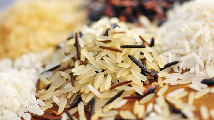 Verschiedene K&ouml;rner Reis liegen bunt gemischt auf einem Tisch und zeigen die Vielfalt der Reisarten in einer ansprechenden Anordnung.