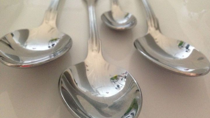 Edelstahlbesteck, darunter L&ouml;ffel, liegt gl&auml;nzend auf einer hellen Oberfl&auml;che und zeigt m&ouml;gliche Verunreinigungen.