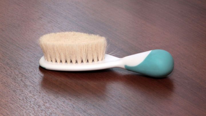 Eine B&uuml;rste liegt auf einem Holztisch. Sie wird verwendet, um den flauschigen Fellkragen nach dem Waschen aufzufrischen.