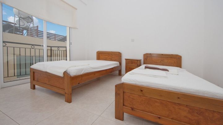 Zwei Einzelbetten stehen in einem hellen Hotelzimmer mit gro&szlig;em Fenster, ideal f&uuml;r k&uuml;hl schlafen bei Hitze.