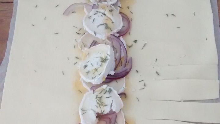 Ziegenk&auml;se und Thymian sind auf einem ausgerollten Teig platziert, bereit zum Falten zu einem leckeren Zopf.