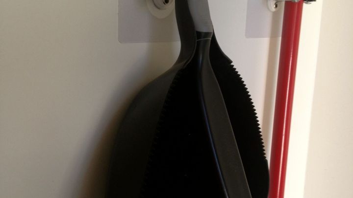 Ein Kehrblech mit Besen h&auml;ngt an einem Haken an der Wand, daneben ein roter Stiel mit dem Text "Vileda" darauf.