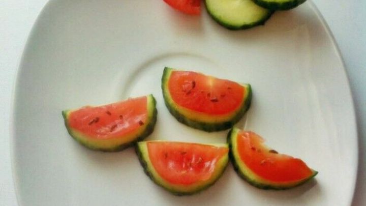 Auf einem wei&szlig;en Teller liegen kleine Melonenst&uuml;cke aus Gurken und Tomaten, die fr&ouml;hlich angerichtet sind.