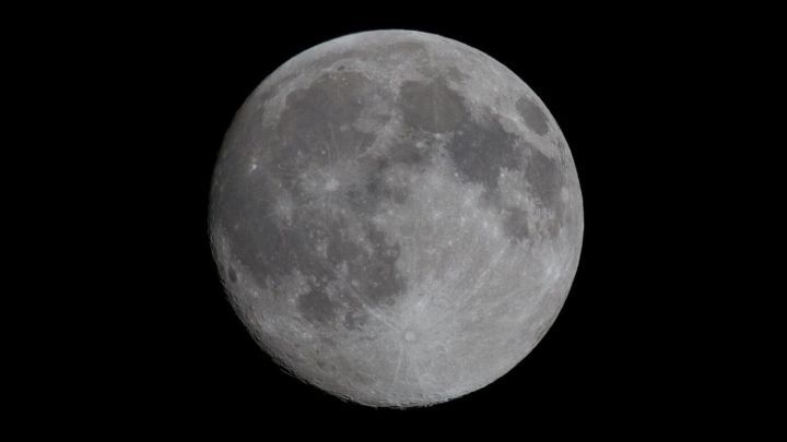 Der Mond leuchtet hell am Nachthimmel und zeigt detaillierte Kraterstrukturen, umgeben von einem tiefschwarzen Hintergrund.