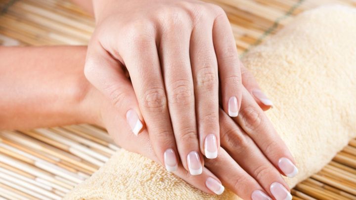 Br&uuml;chige Fingern&auml;gel ruhen sanft auf einem Handtuch, w&auml;hrend gepflegte H&auml;nde entspannen und sich pflegen lassen.