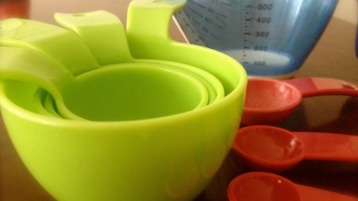 Gr&uuml;ne Messbecher und rote Teel&ouml;ffel liegen bereit, um amerikanische Ma&szlig;einheiten bei Rezepten umzurechnen.