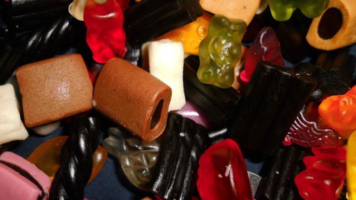 Eine bunte Mischung an S&uuml;&szlig;igkeiten liegt auf einem dunklen Hintergrund. Unterschiedliche Formen und Farben dominieren das Bild.