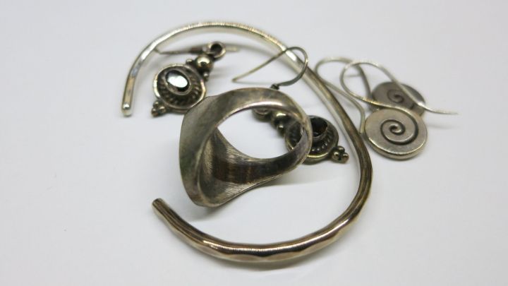 Ein gl&auml;nzendes Schmuckst&uuml;ck liegt auf einem wei&szlig;en Untergrund, w&auml;hrend Bier zur Reinigung benutzt wird.