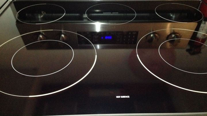 Ein glattes Glaskeramikfeld wird in einer K&uuml;che gezeigt, bereit zur Reinigung mit Grillreiniger. Die Umgebung ist modern eingerichtet.