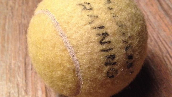 Ein Tennisball liegt ruhig auf einem Holztisch, gekennzeichnet mit "TRAINING".