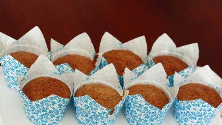 Fluffige Zucchini Muffins stehen auf einem wei&szlig;en Teller, umgeben von einer rustikalen, h&ouml;lzernen Tischoberfl&auml;che.