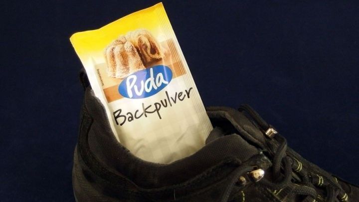 Ein schwarzer Turnschuh mit einem P&auml;ckchen Backpulver steckt im Innenteil. Dies zeigt eine Methode gegen M&uuml;ffel-Turnschuhe.