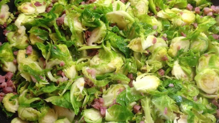 In einer gro&szlig;en Pfanne wird frischer Speckrosenkohl mit kleinen St&uuml;ckchen Speck zubereitet, um eine herzhafte Pasta zuzubereiten.