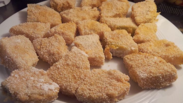 Kohlrabi Nuggets, paniert und bereit zum Frittieren, liegen auf einem wei&szlig;en Teller in der K&uuml;che, nah beieinander.