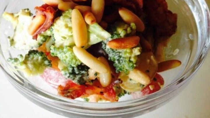 Ein frischer Brokkoli-Salat mit knusprigem Bacon und ger&ouml;steten Pinienkernen in einer Glasschale, appetitlich angerichtet.