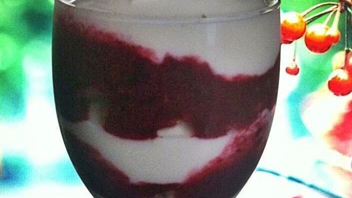 Ein Dessertbecher mit Beeren-Fool zeigt schichtweise roten Beerensirup und cremige Masse, dekoriert mit Beeren.