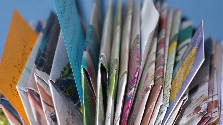 Ein bunter Notizhalter besteht aus gefalteten Katalogseiten, kreativ angeordnet auf einem blauen Hintergrund.