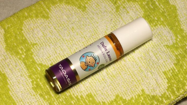 Eine kleine Flasche mit einem Duft&ouml;l liegt auf einem leuchtend gr&uuml;nen Handtuch, ideal f&uuml;r Maschinenw&auml;sche ohne Weichsp&uuml;ler.