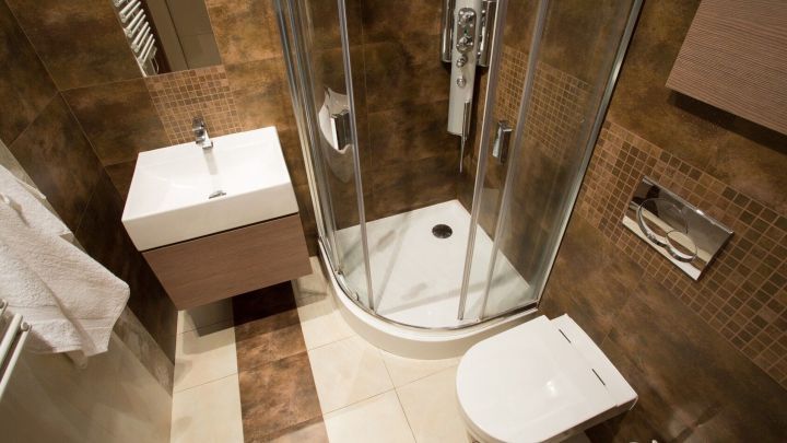 Bad mit Dusche zeigt moderne Einrichtung in kleinem Raum; Waschbecken und WC betonen effiziente Nutzung.