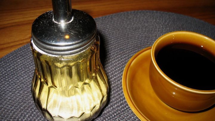 Ein gl&auml;serner Kaffeewei&szlig;er steht auf einem Tisch neben einer Tasse Kaffee, bereit zum portionieren.