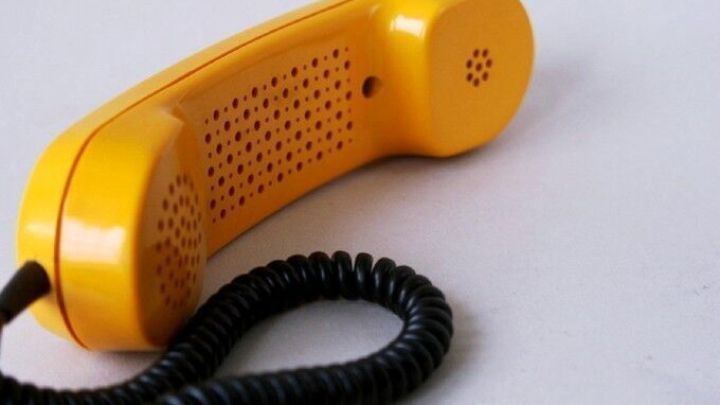 Ein gelber Telefonh&ouml;rer liegt auf einem Tisch. Er symbolisiert den Enkeltrick, der oft bei &auml;lteren Menschen angewendet wird.