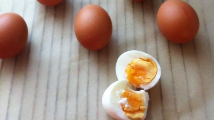 Eier liegen auf einer Oberfl&auml;che, w&auml;hrend eines aufgeschnitten und gekocht ist, mit weichem Eigelb sichtbar.