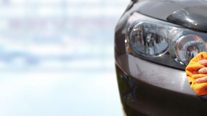Ein Auto wird mit einem Tuch gereinigt, um die Kunststoffteile aufzufrischen. Die Umgebung wirkt hell und modern.