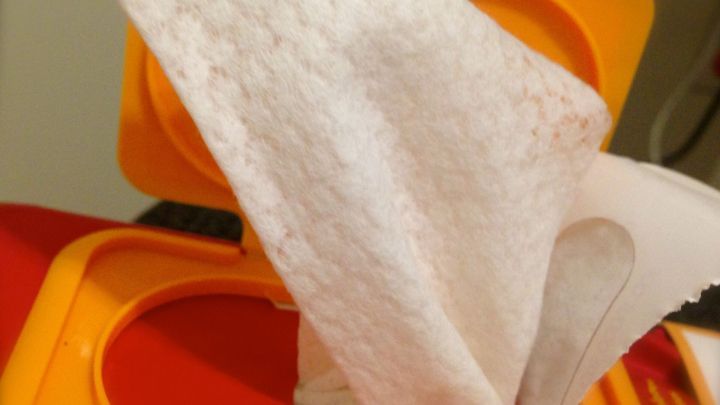 Ein einzelnes Abschminktuch wird aus einer orangefarbenen Verpackung gezogen, um Hautschminke sanft zu entfernen.