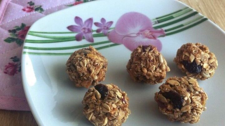 F&uuml;nf leckere M&uuml;slib&auml;llchen liegen auf einem dekorierten Teller, umgeben von einer sanften, bl&uuml;henden Unterlage.