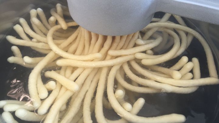 Sp&auml;tzle selber machen: Sp&auml;tzleteig wird durch die Presse in kochendes Wasser gepresst.