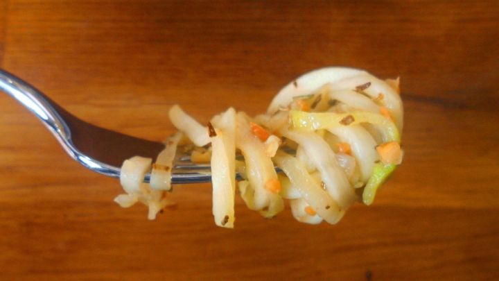 Zucchinispaghetti liegen auf einer Gabel, umgeben von einer Holzoberfl&auml;che, bereit zum Genie&szlig;en mit Rosmarin-Mandel-Butter.
